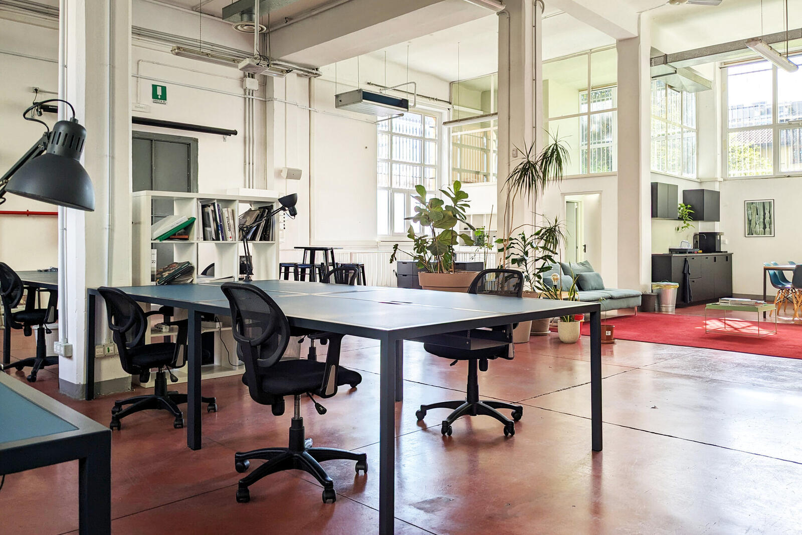 Postazioni di lavoro con lampade e scaffali nell'open space di C4 Workspace